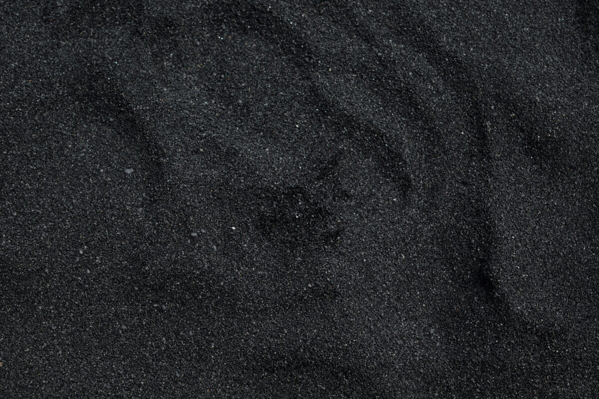 Close-up of black sand texture from Waimea Beach in Hawaii. Ideal for backgrounds.