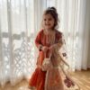 Girl wearing a burnt orange hand-painted garara set with a lace-trimmed shirt and floral organza dupatta
