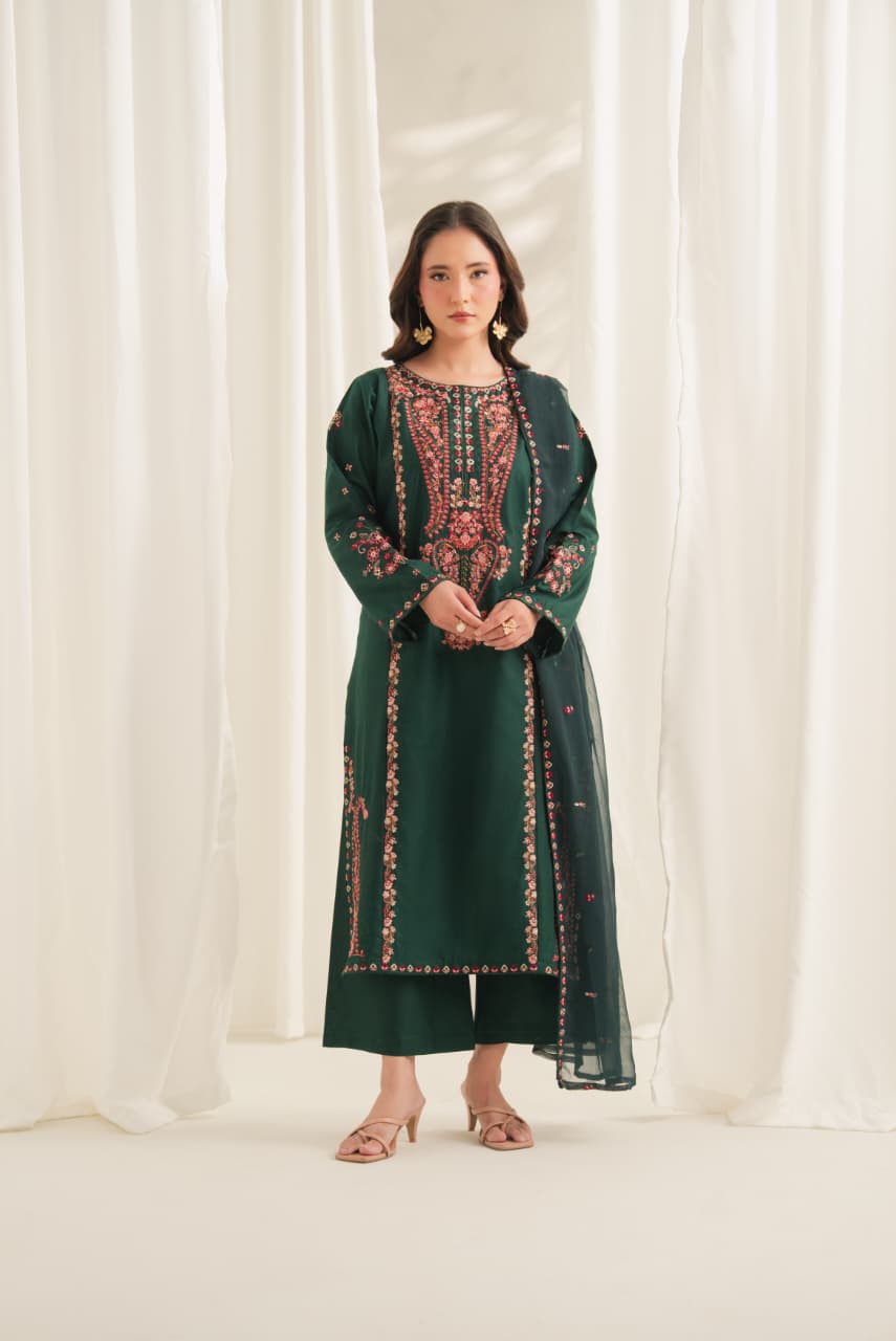 Woman wearing an emerald green embroidered Pakistani 3 piece suit with floral neckline, embroidered borders and organza dupatta